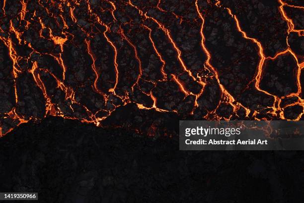 night time image showing the edge of a glowing lava plain, iceland - volcanic rock - fotografias e filmes do acervo