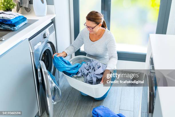 mujer cargando la lavadora con la ropa - laundry fotografías e imágenes de stock