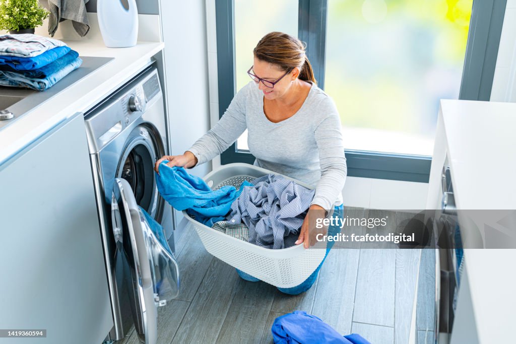 Femme chargeant la machine à laver avec le linge