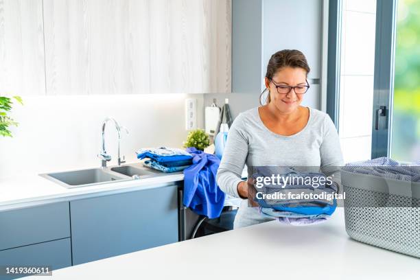 woman holding folded clean clothes after wash machine - clean laundry stock pictures, royalty-free photos & images