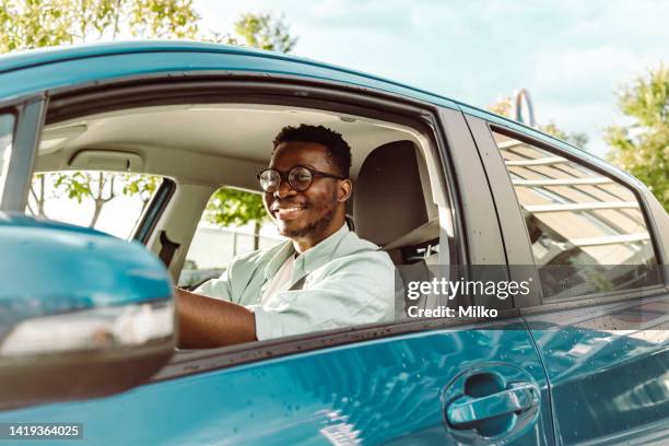 happy male driver holding steering wheel and driving a car - driving stock pictures, royalty-free photos & images