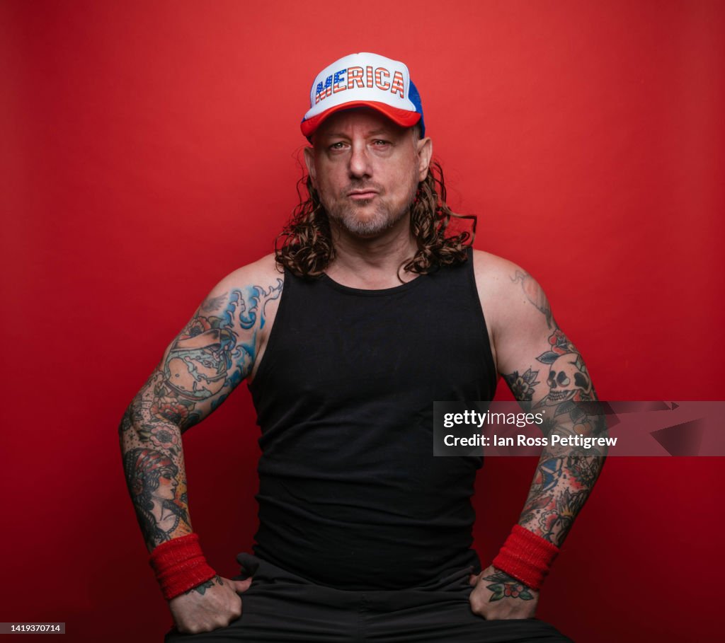 Redneck man with tattoos and mullet wearing "Merica" hat