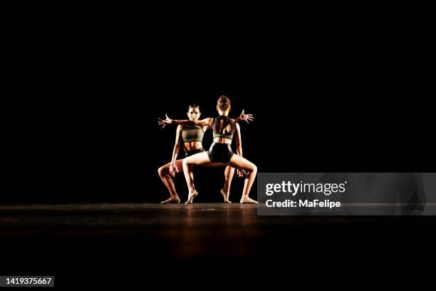 girl duet performing contemporary dance on dark stage - contemporary dance stock pictures, royalty-free photos & images