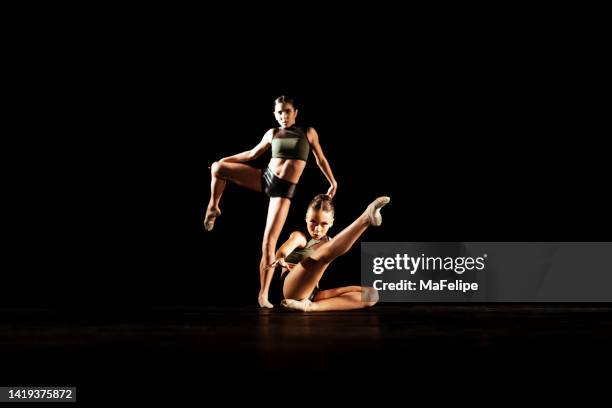 girl duet performing contemporary dance on dark stage - contemporary dance stock pictures, royalty-free photos & images