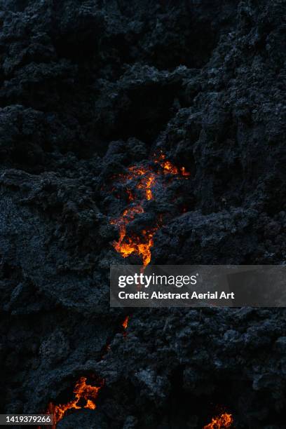 boiling lava covered by volcanic rock photographed from extremely close up, iceland - vulkanisch gesteente stockfoto's en -beelden