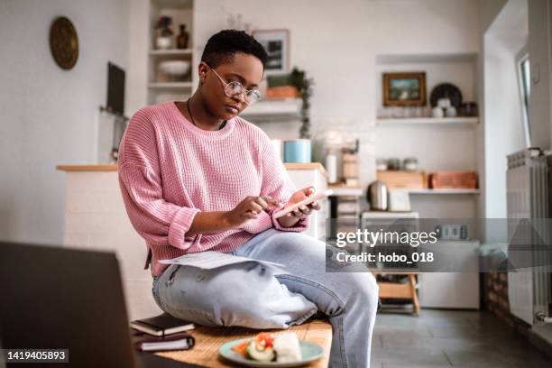 mujer joven haciendo finanzas en casa por la mañana - finanzas domésticas fotografías e imágenes de stock