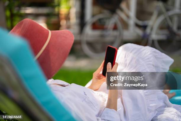 woman using smartphone on sunbed - zonnebank stockfoto's en -beelden