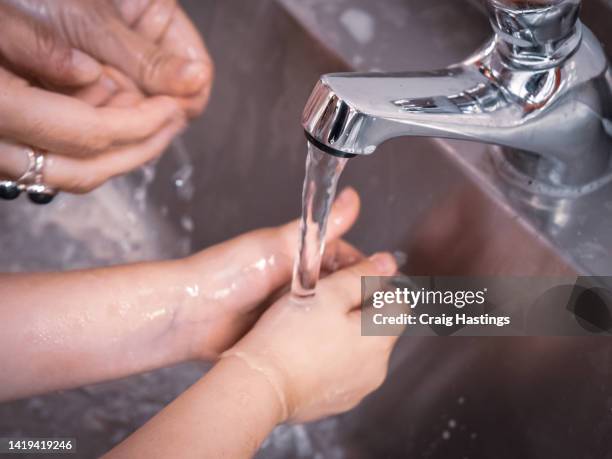 parent teaching child how to wash hands properly in the kitchen sink. - running water isolated stock pictures, royalty-free photos & images