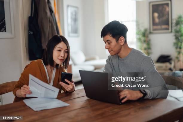 couple going through financial bills and making financial plans with laptop - ノートパソコン スマートフォン ストックフォトと画像