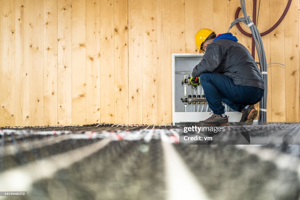 Plumber mounting underfloor heating manifold