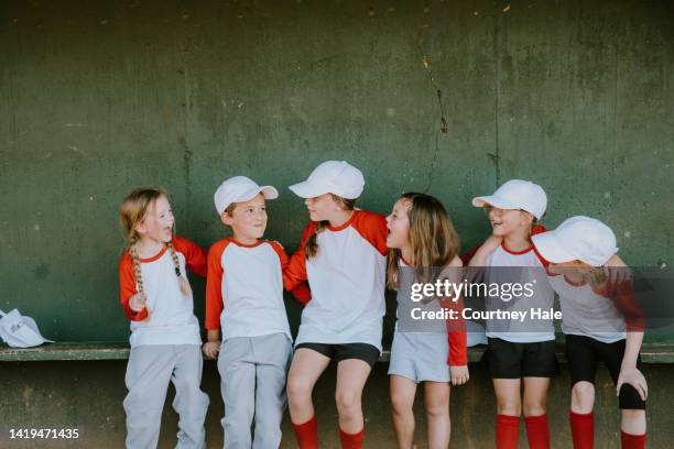 elementary age children are athletes playing little league baseball together on co-ed sports team with coaches at ballfield - banco dos jogadores imagens e fotografias de stock