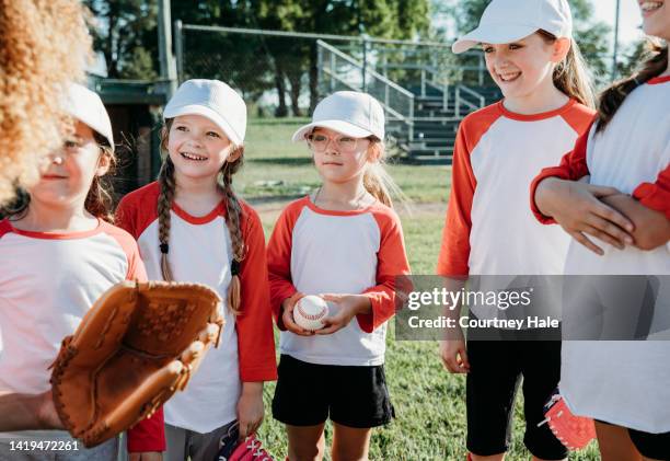 elementary age children are athletes playing little league baseball together on co-ed sports team with coaches at ballfield - baseball huddle stock pictures, royalty-free photos & images