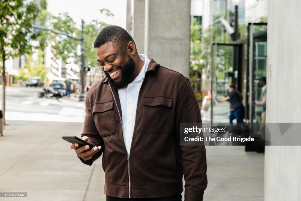 Smiling businessman talking on smart phone on city street