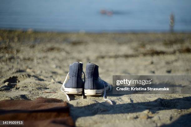 blue canvas shoes on a beach - blauwe schoen stockfoto's en -beelden