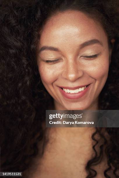 closeup portrait of beautiful young woman with curly hair style and closed eyes. the woman has white toothy smile and freckles. the mulatto is a representative of a mixed race, an african american and a white race. - face close up bildbanksfoton och bilder