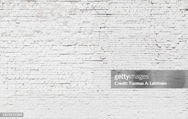 uneven, aged and weathered brick wall, plastered and painted in white. - brick foto e immagini stock
