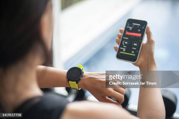 athlete women checking sport application and smart watch after training. - asian and indian ethnicities smartwatch phone stock pictures, royalty-free photos & images