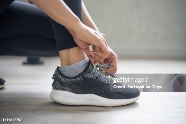 asian fitness instructor tying shoelace at the gym. - lacing trainers stock pictures, royalty-free photos & images