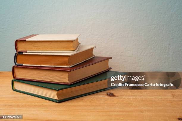 a stack of old hardcover books on wooden table - romance book covers fotografías e imágenes de stock