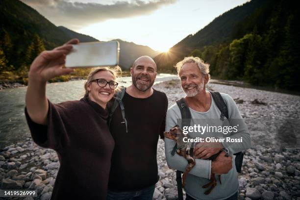 happy friends taking selfie at a riverbank at sunset - 55 years old white man active stock pictures, royalty-free photos & images