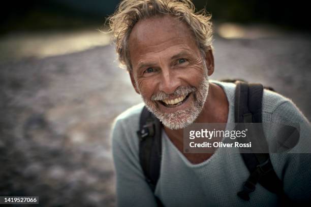 portrait of a happy mature man at a riverbank - bayern menschen stock-fotos und bilder