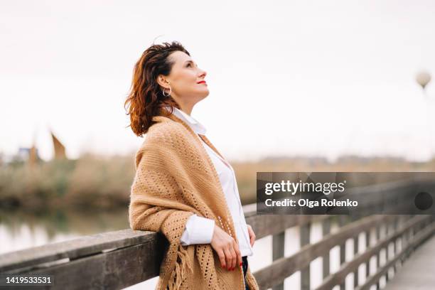 lonely beautiful mature woman walk alone in the part at autumn day - widow stock pictures, royalty-free photos & images