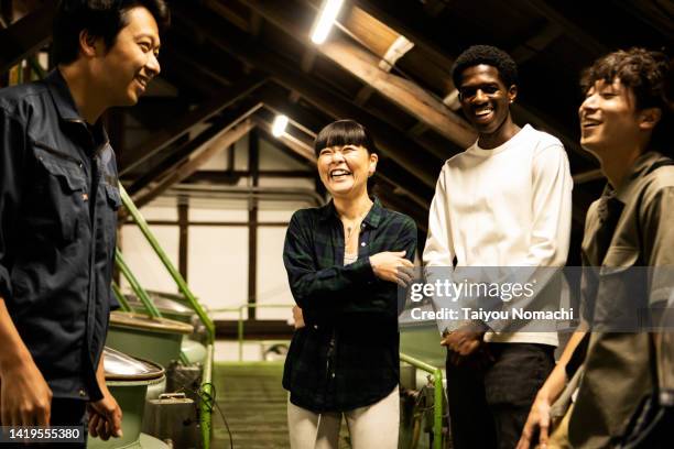 tourists on a trip to japan visit a sake brewery and listen to an explanation from a craftsman. - commerce and culture ストックフォトと画像
