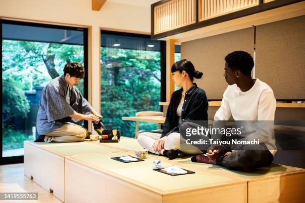a tea ceremony experience for tourists visiting japan at the guesthouse. - washitsu stock pictures, royalty-free photos & images