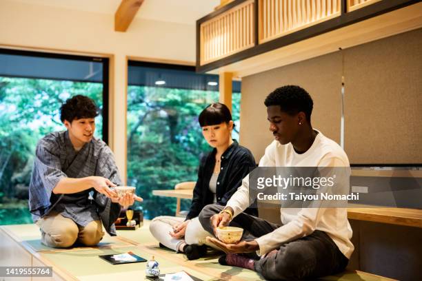 tourists learn how to drink powdered green tea during a tea ceremony experience. - tea ceremony stock-fotos und bilder