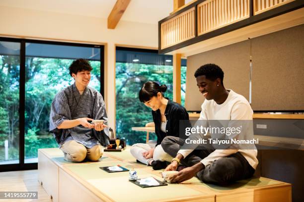 tourists learn how to drink powdered green tea during a tea ceremony experience. - tokyo food stock pictures, royalty-free photos & images