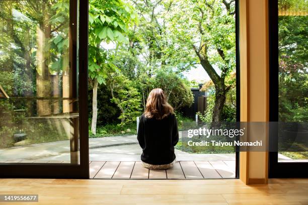 the back view of a female guest relaxing on the porch of the guesthouse where she stayed during her trip to japan. - public building ストックフォトと画像