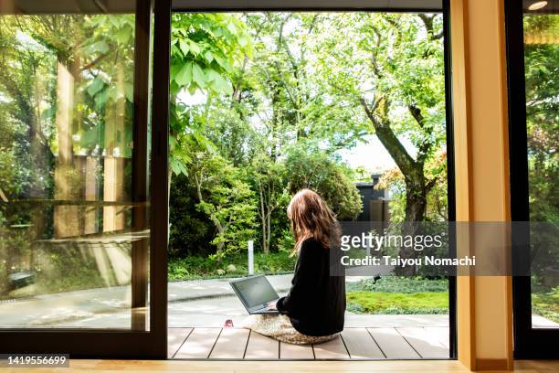 a female guest working on the porch of the guesthouse where she stayed during her trip to japan. - japanese woman bildbanksfoton och bilder