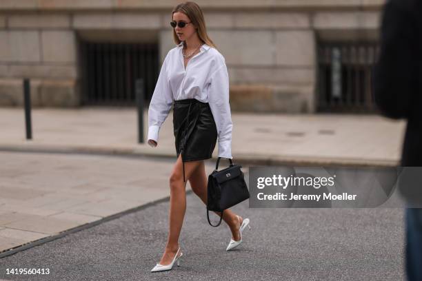 Isabelle Hartmann is seen wearing Balenciaga black round shades, Prada white logo leather heels, Hermes black leather Kelly bag, Tiffany & Co City...