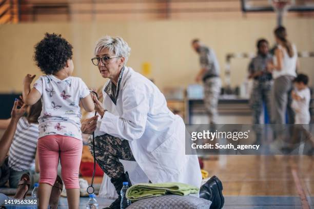 army doctor with civilians after natural disaster - refugee crisis stock pictures, royalty-free photos & images