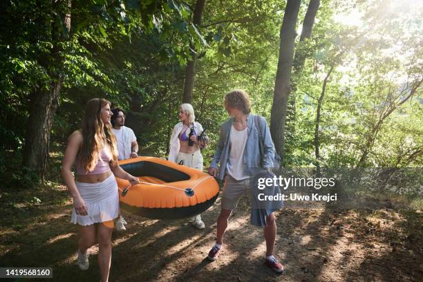 friends carrying inflatable raft - bote neumático fotografías e imágenes de stock