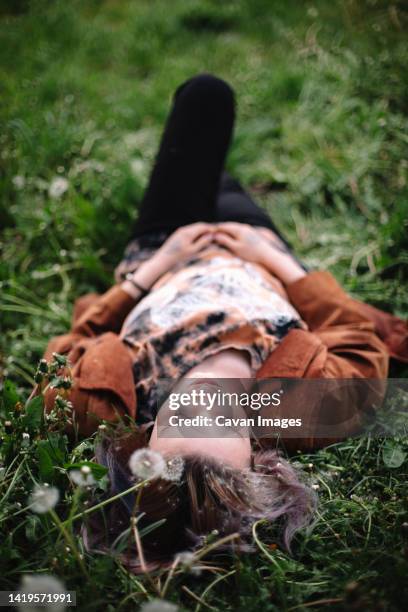 peaceful young woman lying on grass in spring - natural land state stock pictures, royalty-free photos & images