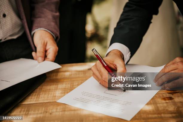 groom's hand signing the registry at a civil wedding - gastenboek stockfoto's en -beelden