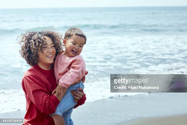 a mother and a boy frolic on the beach. - knöcheltief im wasser stock-fotos und bilder