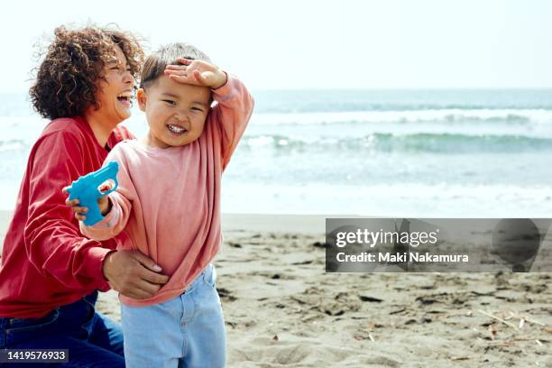 a mother and a boy frolic on the beach. - mother and child in water at beach stock pictures, royalty-free photos & images