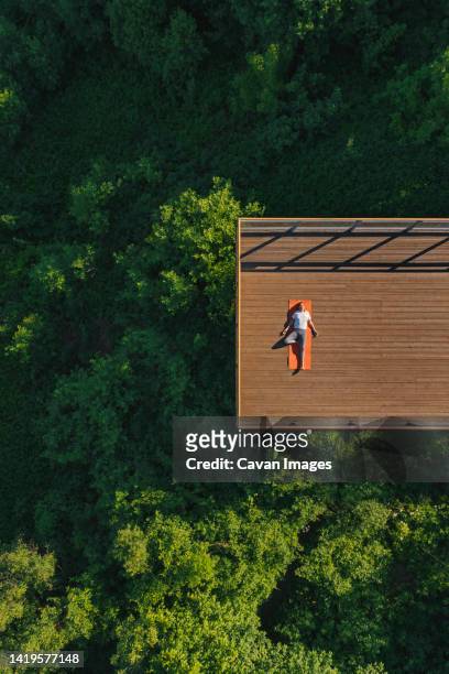 young woman doing yoga on the balcony - latvia forest stock pictures, royalty-free photos & images