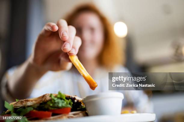 eintauchen von pommes frites in ketchup im restaurant - dipping sauce stock-fotos und bilder