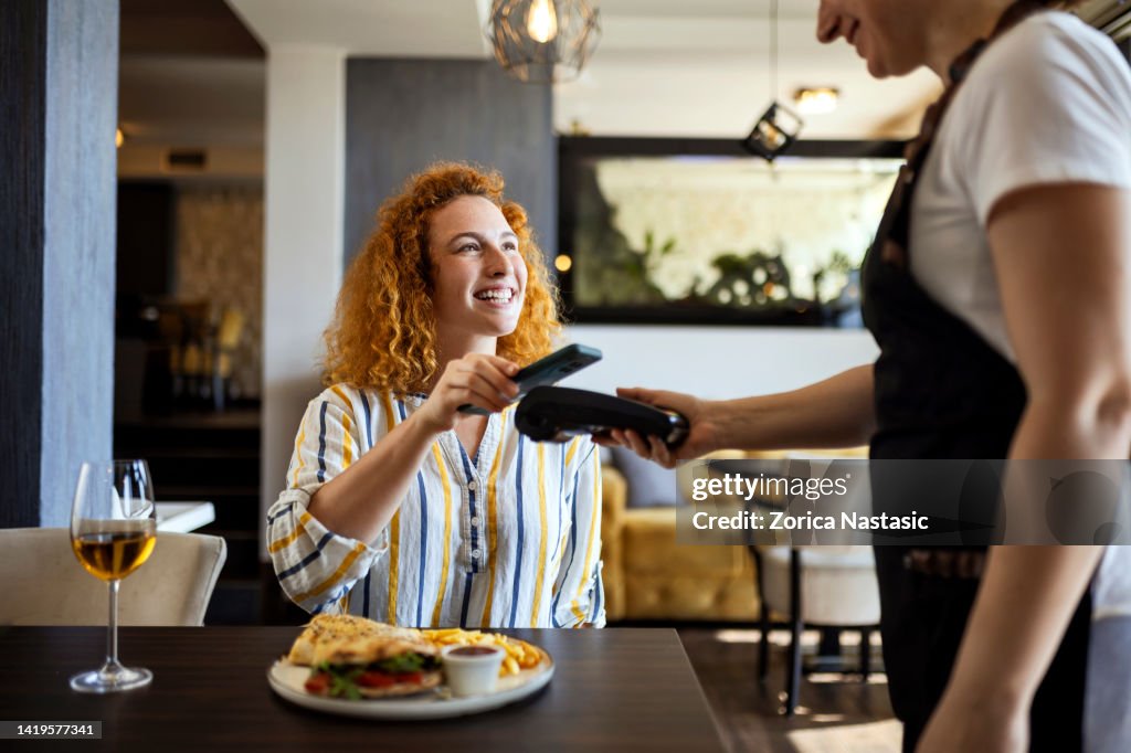 Smiling young making contactless payment with smart phone