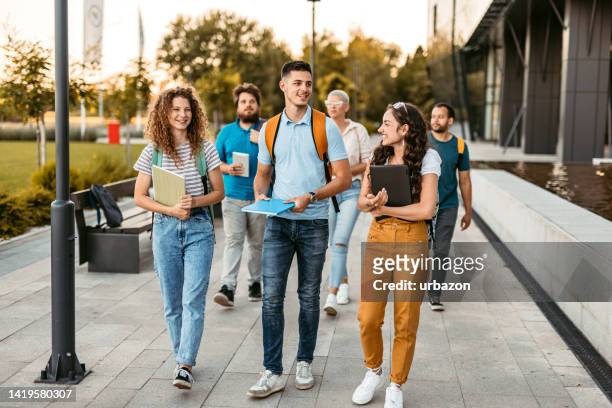students walking  on the university campus - fun student stockfoto's en -beelden