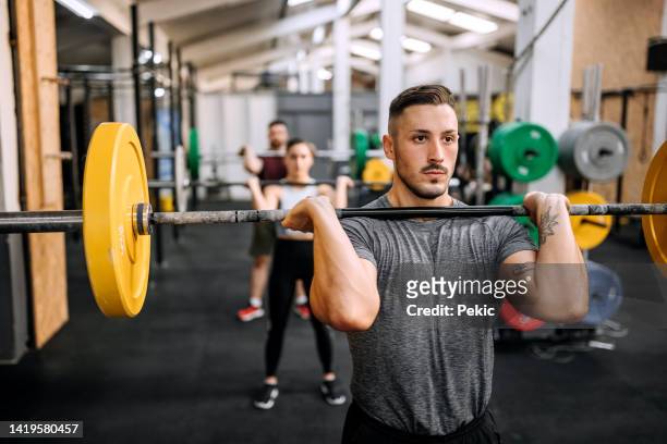 muscular man lifting barbell - sportoefening stockfoto's en -beelden