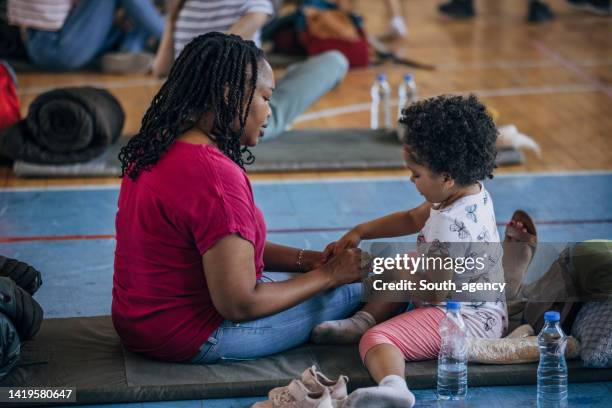 mother and child in shelter after natural disaster - refugee crisis stock pictures, royalty-free photos & images