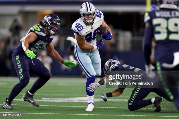 Tight end Jake Ferguson of the Dallas Cowboys carries the ball against linebacker Tanner Muse of the Seattle Seahawks in the first half of a NFL...