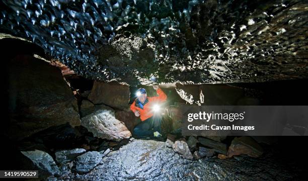 scientist exploring the leidarendi lava cave in iceland - spelunking ストックフォトと画像