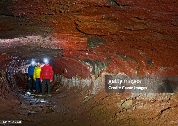 group of scientists exploring the leidarendi lava cave in iceland - potholing stock pictures, royalty-free photos & images