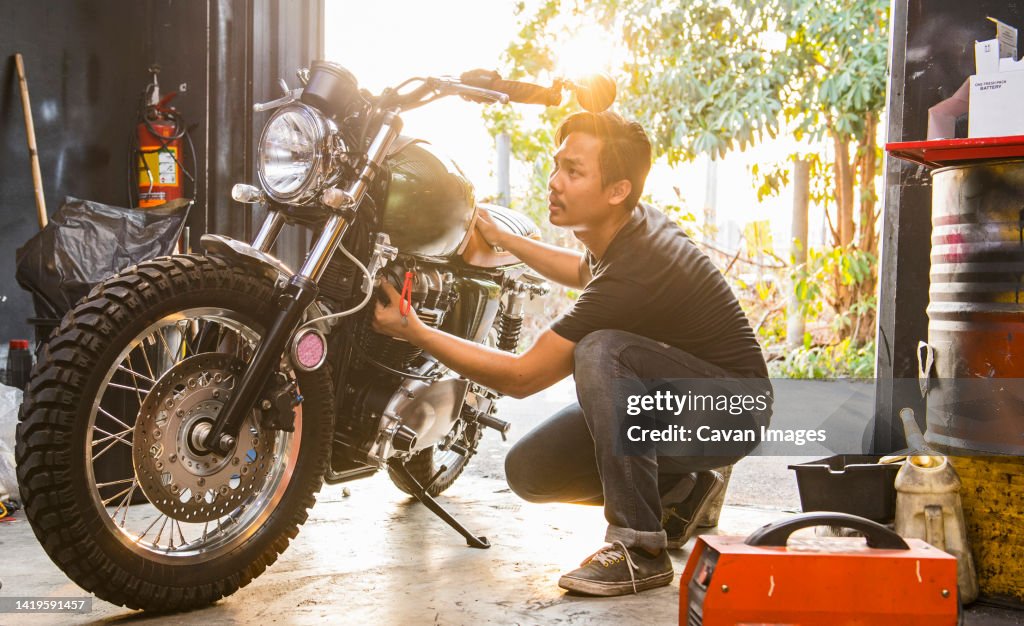 Mechanic working on motorcycle at custom bike shop in Bangkok