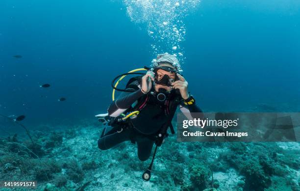 woman ascending into the clear water at the tubbataha reef - aqualung diving equipment stock pictures, royalty-free photos & images